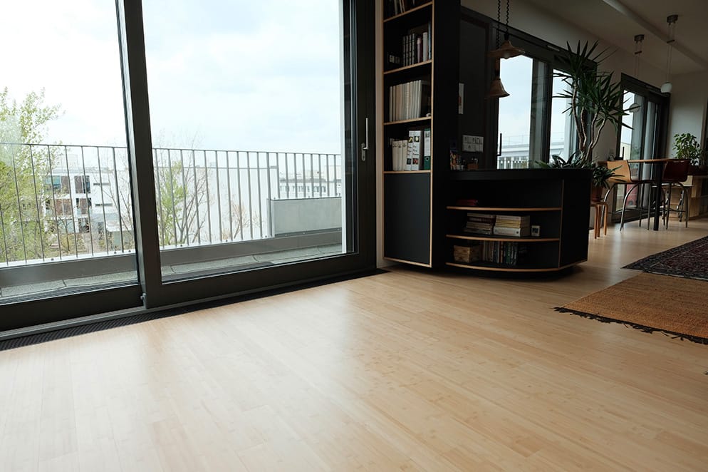 Woonkamer met lichte horizontale bamboe vloer bij de balkondeur